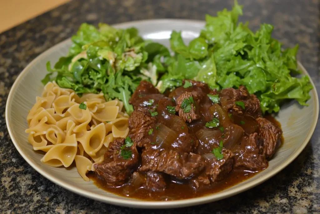 Serving of crockpot beef tips and noodles with a side salad